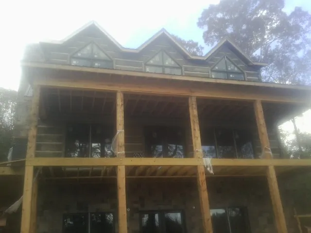 Dormers and porch framing on a large log home under construction — Roof Coating work by our crew in Eola