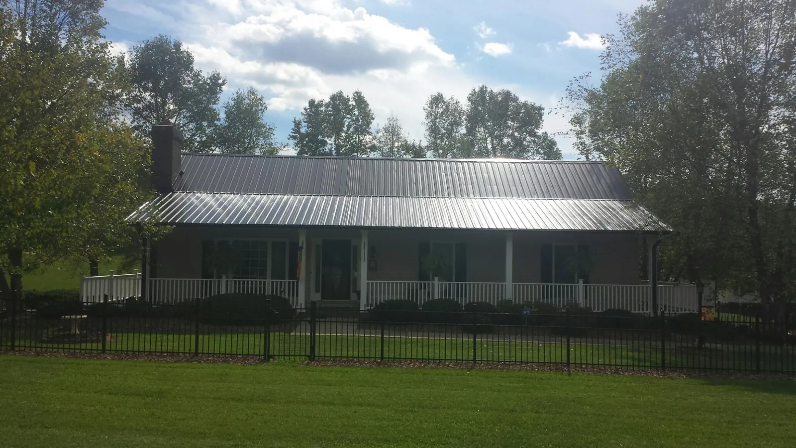 Gray metal roof on a brick ranch with a full width front porch — Gutter Guard Installation work by our crew in Eola