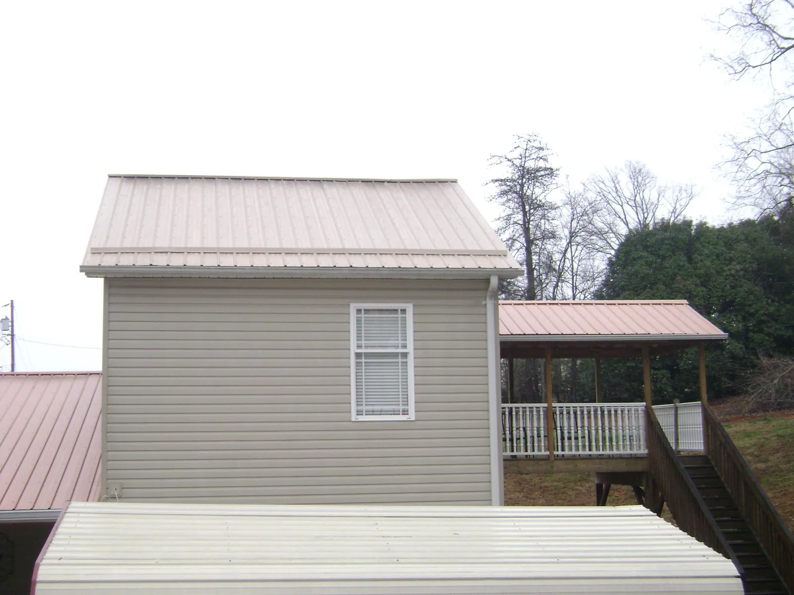 Tan metal roofs on a two story addition and attached porch, from a Roof Replacement job in Eola