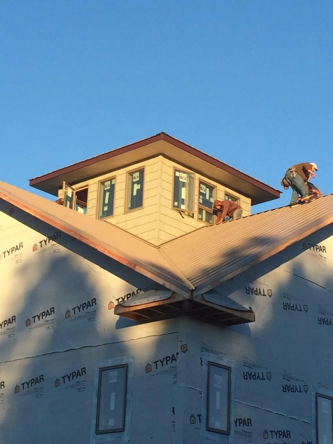 Roofers working around a rooftop cupola on a new metal roof at sunset — Roof Waterproofing in Eola by Roofing Brothers